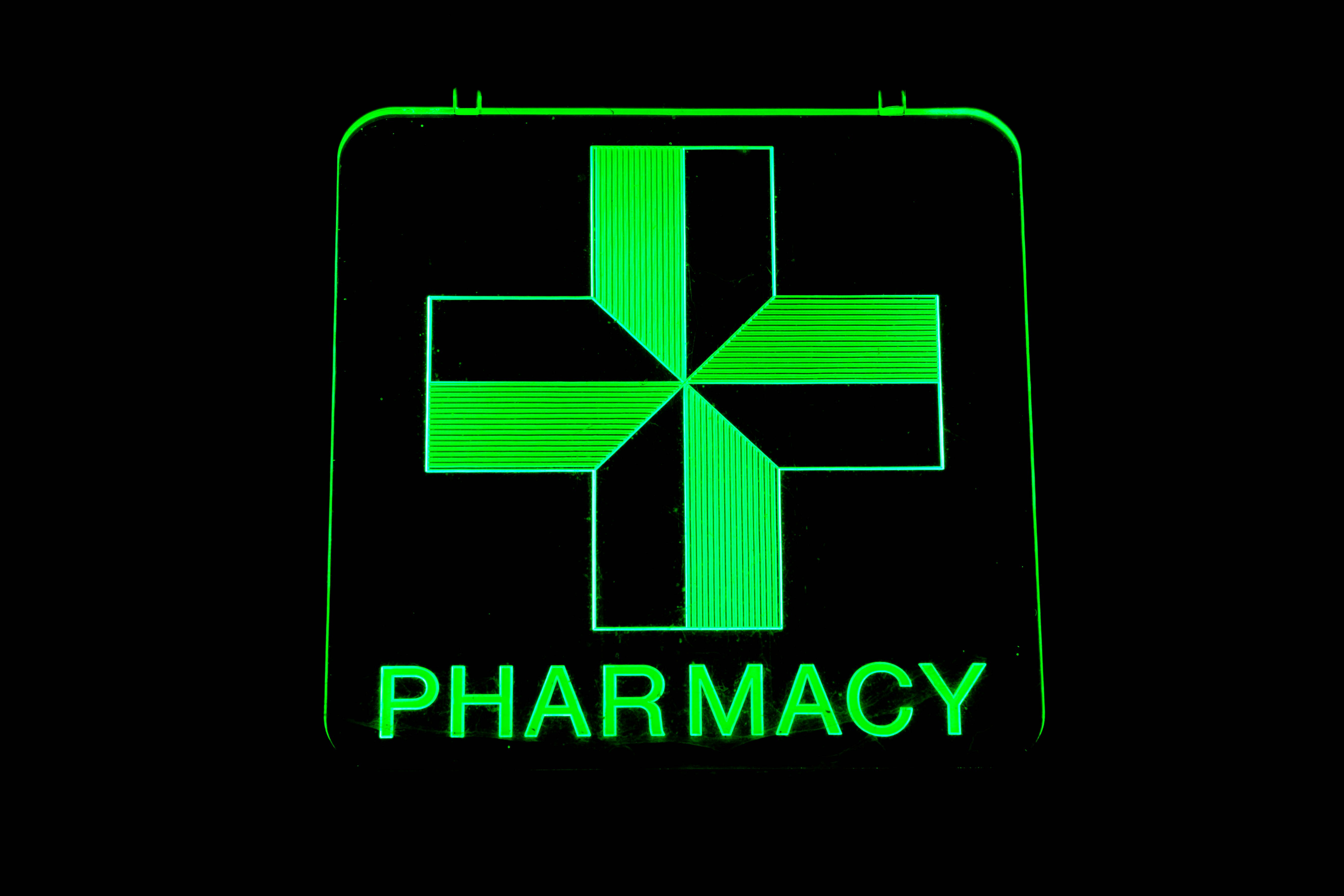 Green pharmacy sign with a cross on it